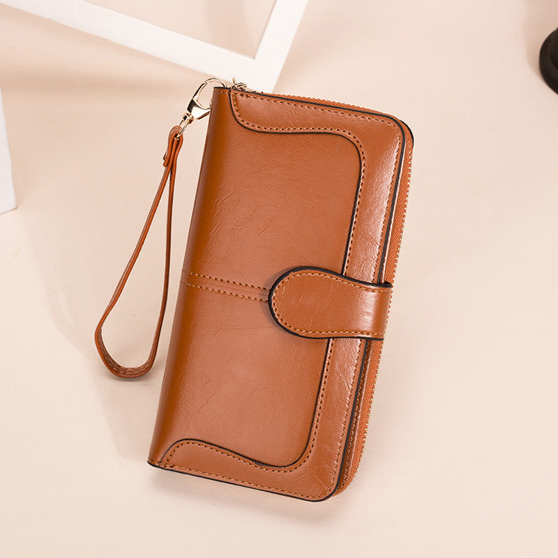 Brown leather wallet with a strap on a beige background