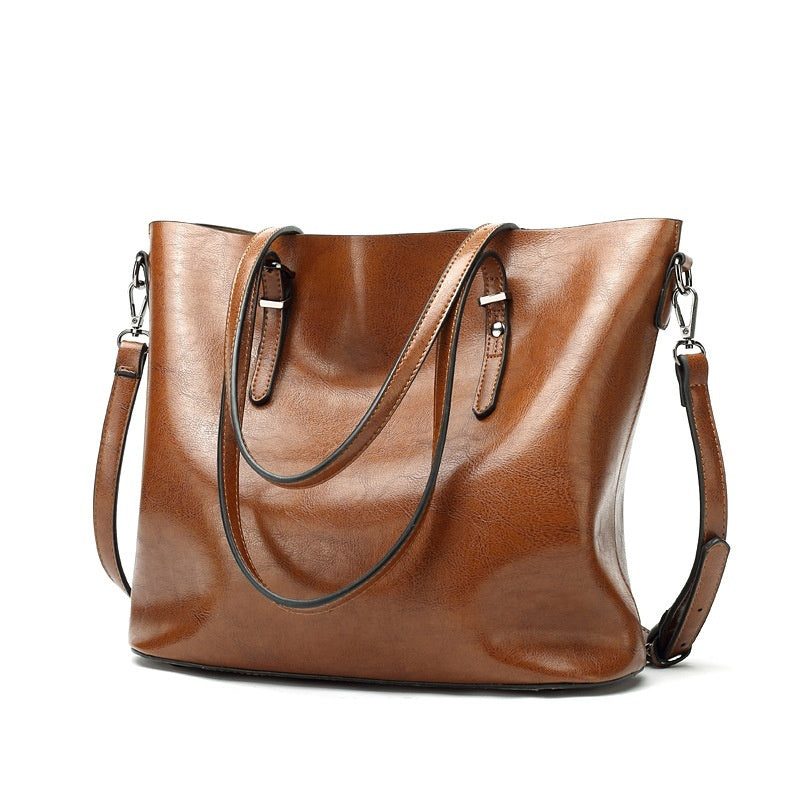Women's retro oil wax leather shoulder bag in brown, angled view showing dual handles, silver hardware and detachable strap