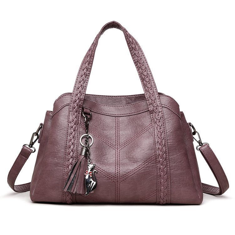 Purple handbag with braided handle and charm on a white background