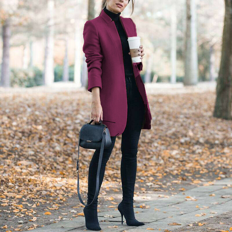 Woman in a burgundy coat holding a coffee cup in an autumn setting