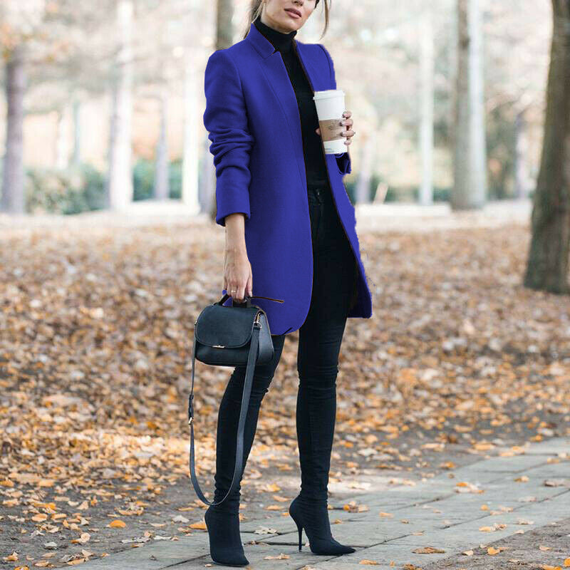 Woman in a blue coat holding a coffee cup in an autumn setting