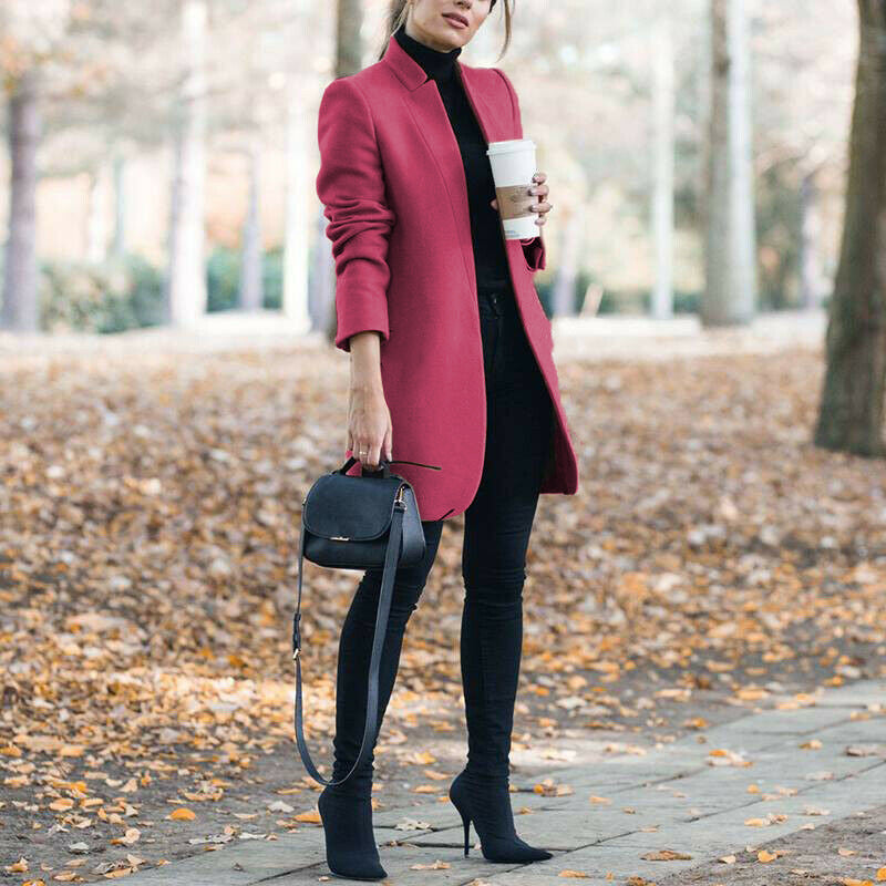 Woman in a red coat holding a coffee cup in an autumn setting