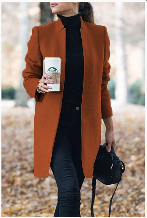 Person wearing a brown coat holding a Starbucks cup outdoors.