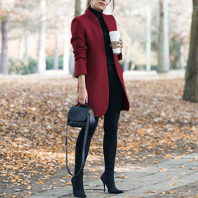Woman in a red coat walking outdoors on a leaf-covered path