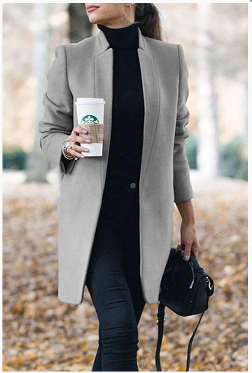 Person wearing a gray coat holding a Starbucks cup outdoors.