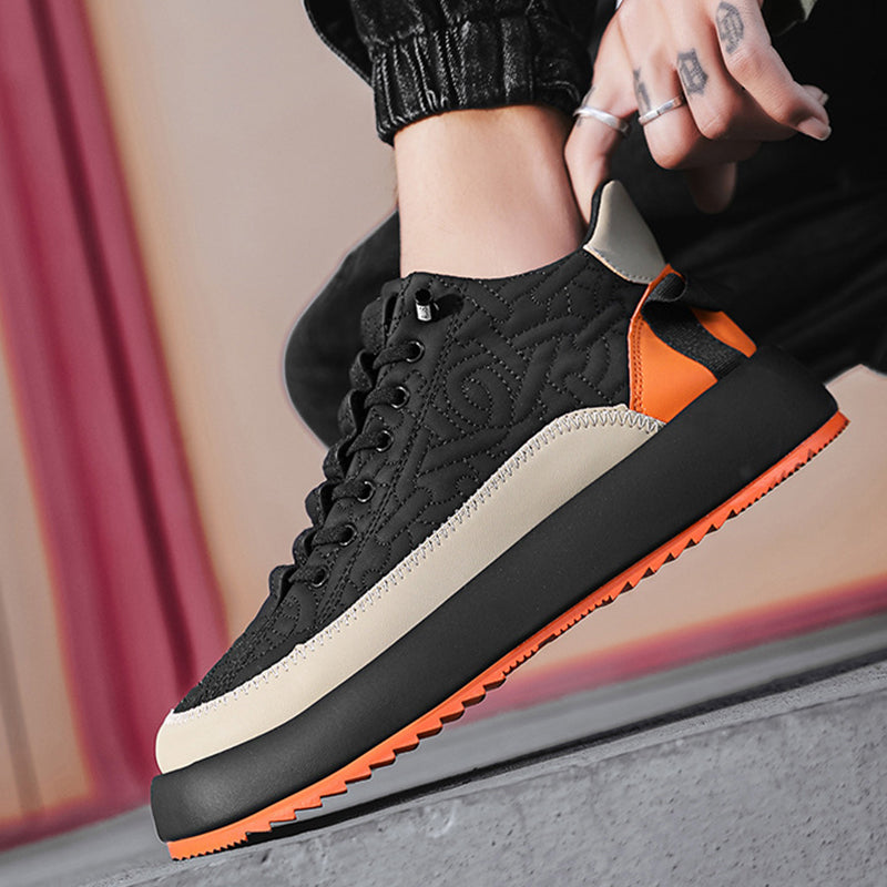 Black and orange sneaker worn by a person with a blurred background