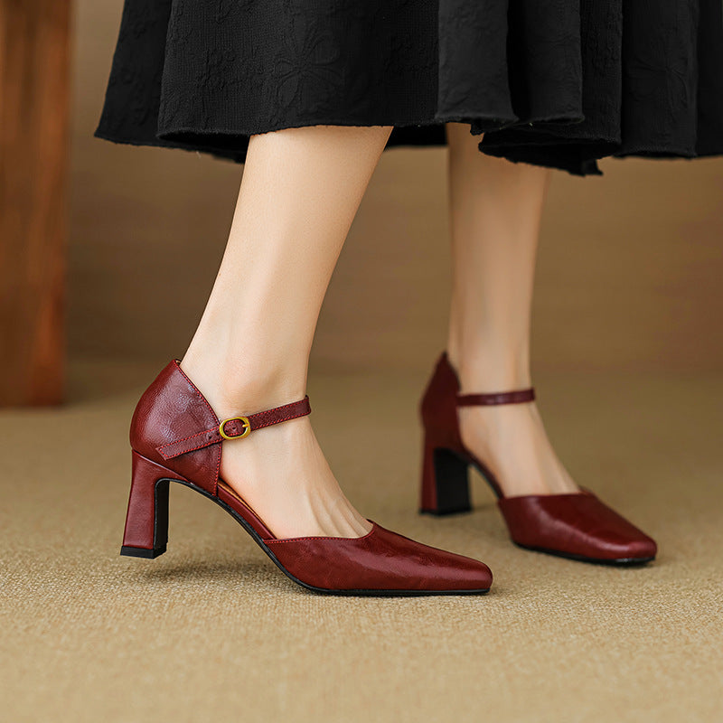Red high-heeled shoes worn with a black skirt on a beige background