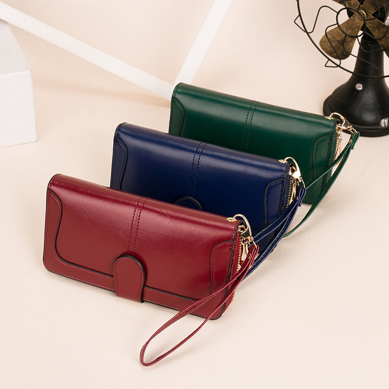 Three leather handbags in red, blue, and green on a light beige surface.