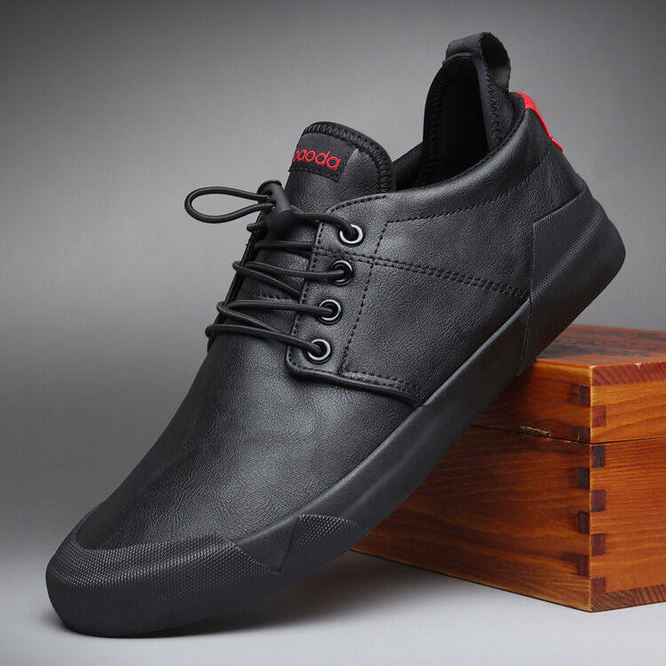 Black leather shoe with a wooden box on a gray background