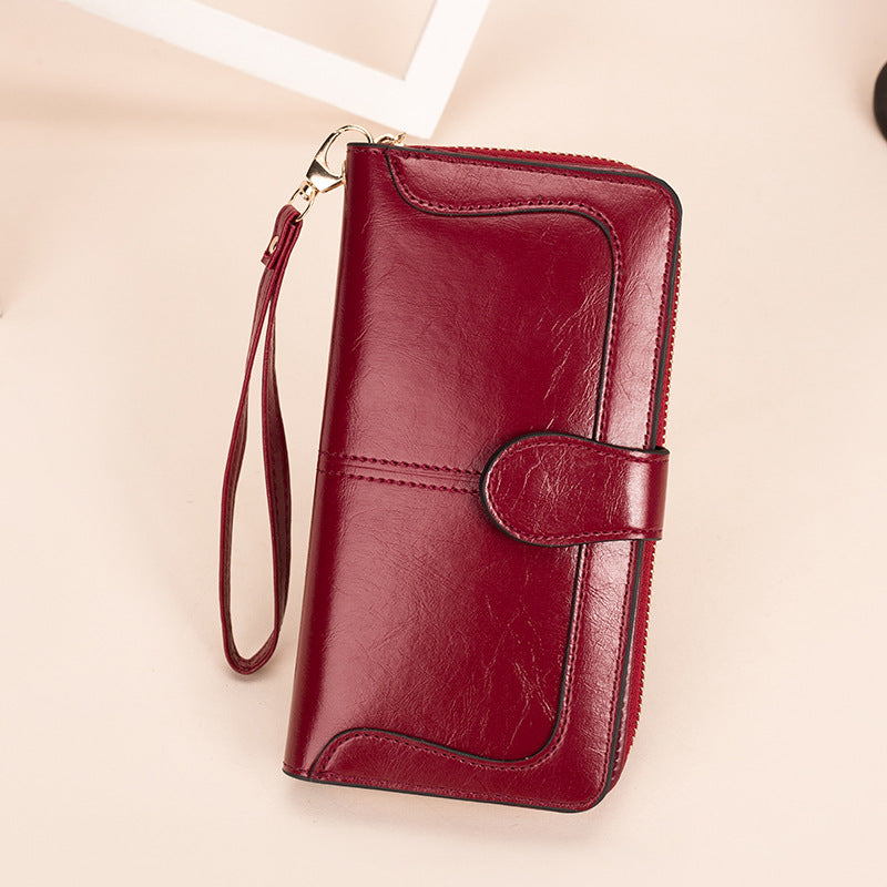 Red leather wallet with a strap on a beige background