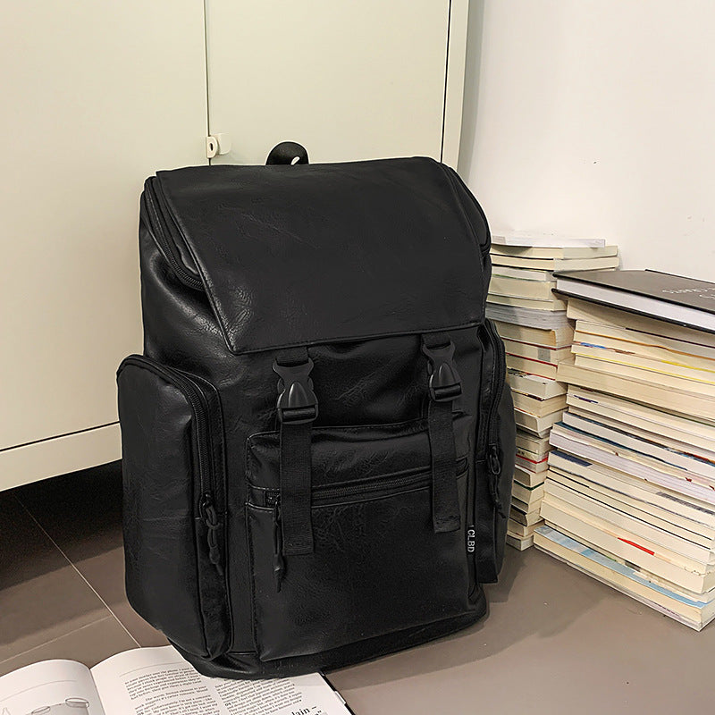 Black backpack on a floor next to a stack of books