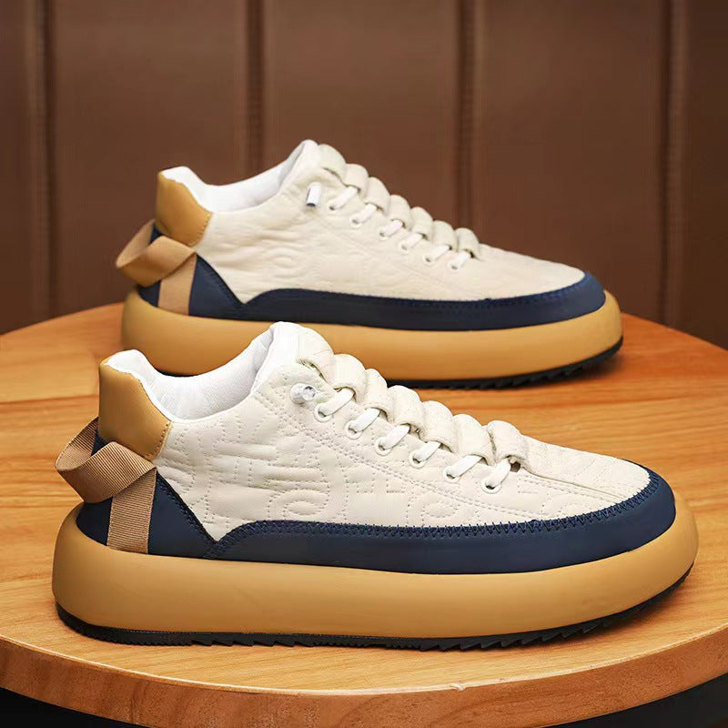 Pair of white sneakers with blue and brown accents on a wooden surface.