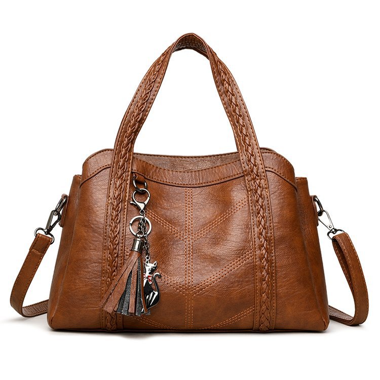 Brown leather handbag with a decorative charm on a white background