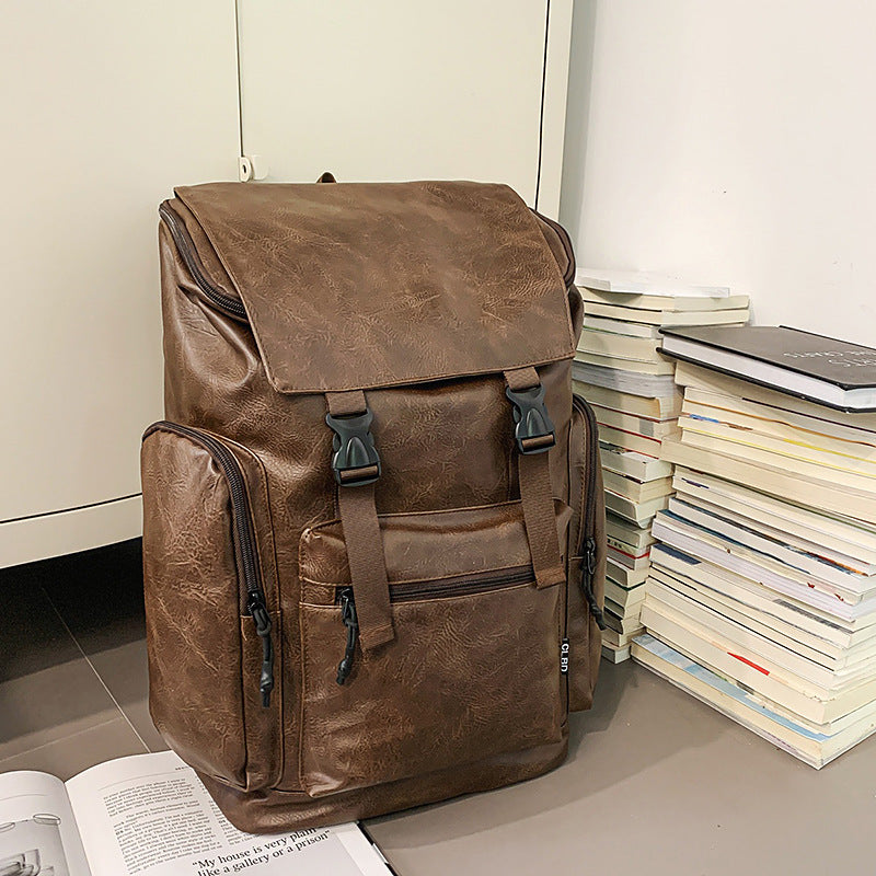 Brown leather backpack on a surface with books around it