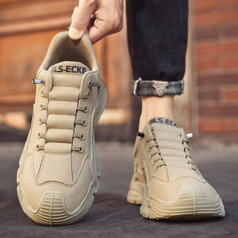 Beige sneakers being held up with a blurred background