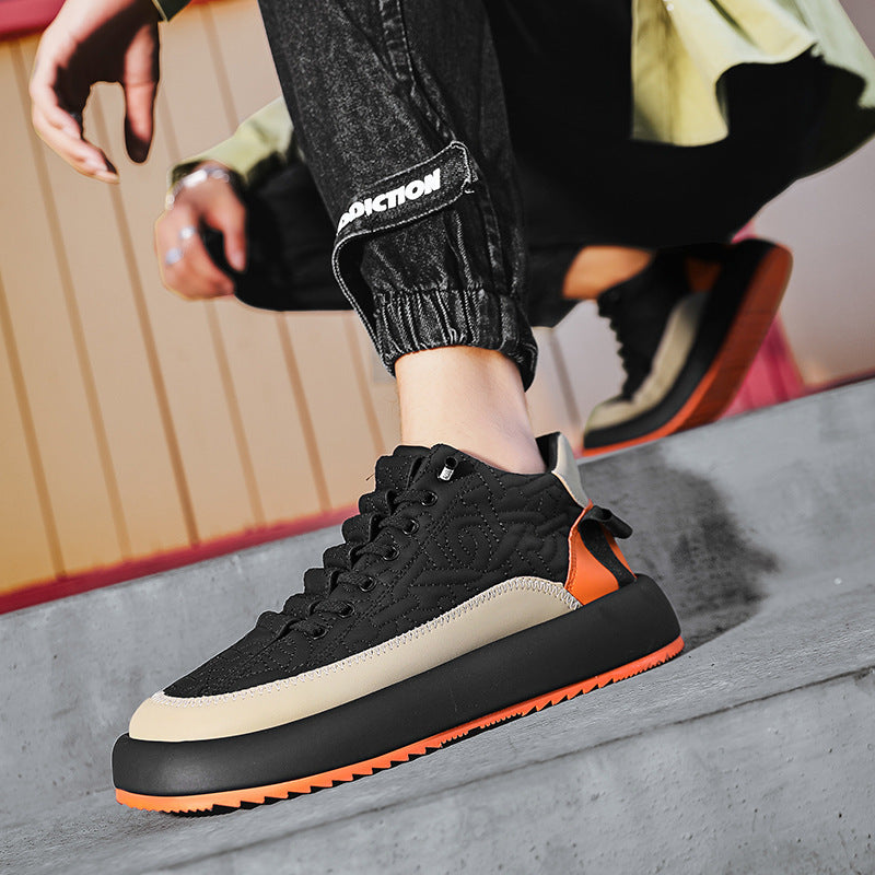 Black and orange sneaker worn by a person sitting on a bench.