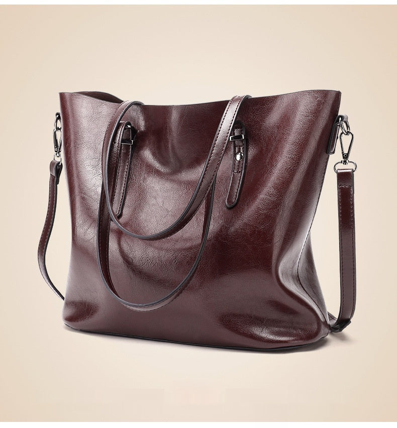 Women's oil wax leather shoulder bag in coffee color, angled front view highlighting rich leather texture and dual top handles
