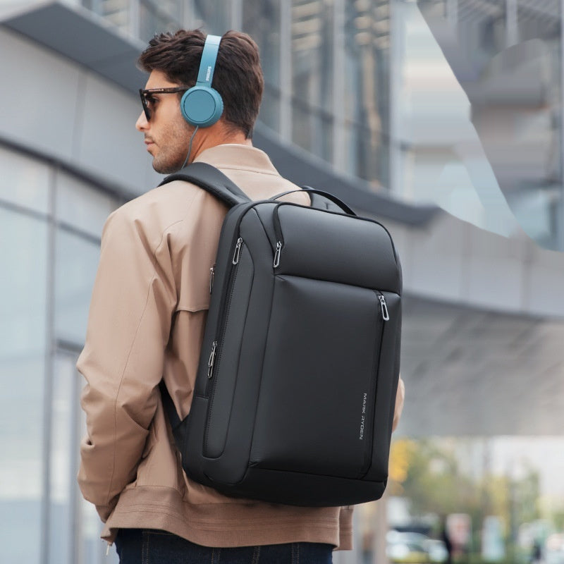 Man wearing a black backpack and blue headphones, standing outdoors.