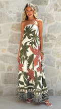 Woman wearing a strapless floral dress against a stone wall.