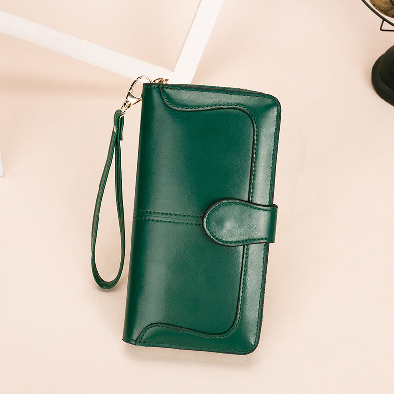 Green leather wallet with wrist strap on a beige background