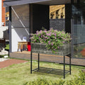 Garden planter with flowers on a stand in front of a modern house.