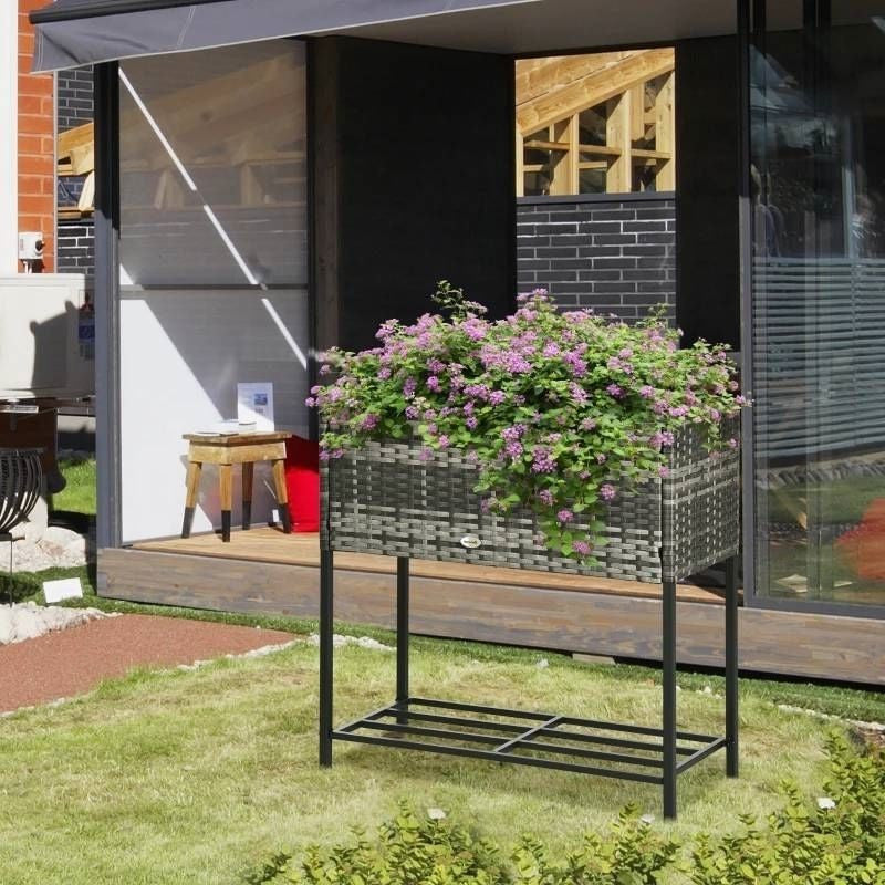 Garden planter with flowers on a stand in front of a modern house.