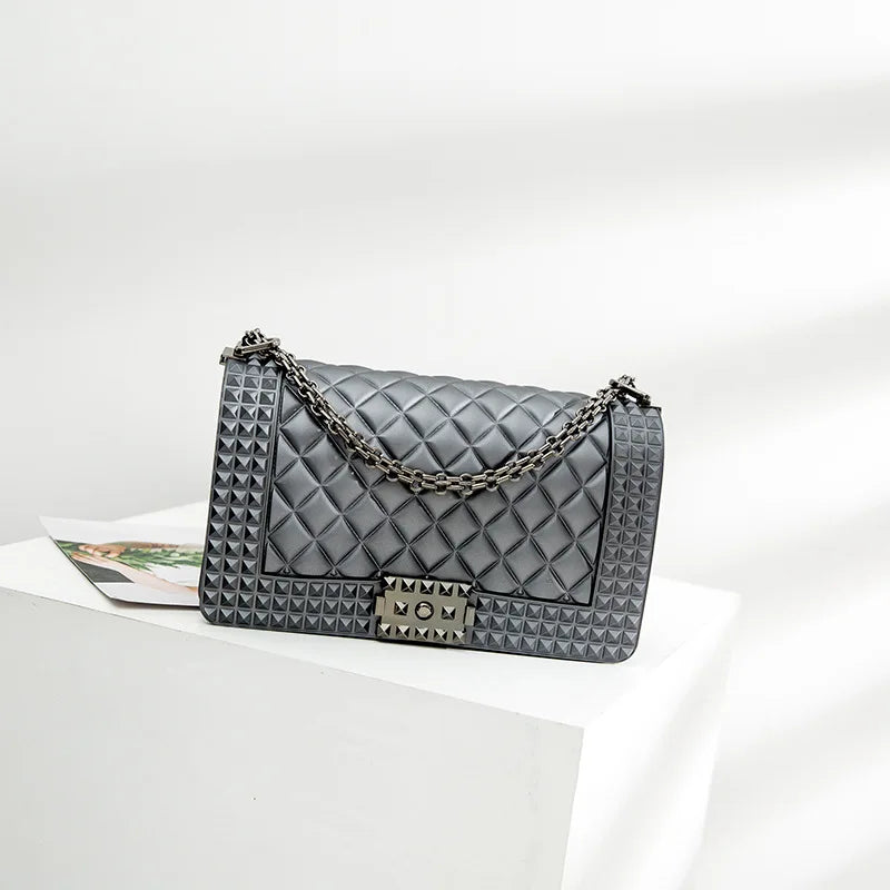 Gray quilted handbag with chain strap on a white surface