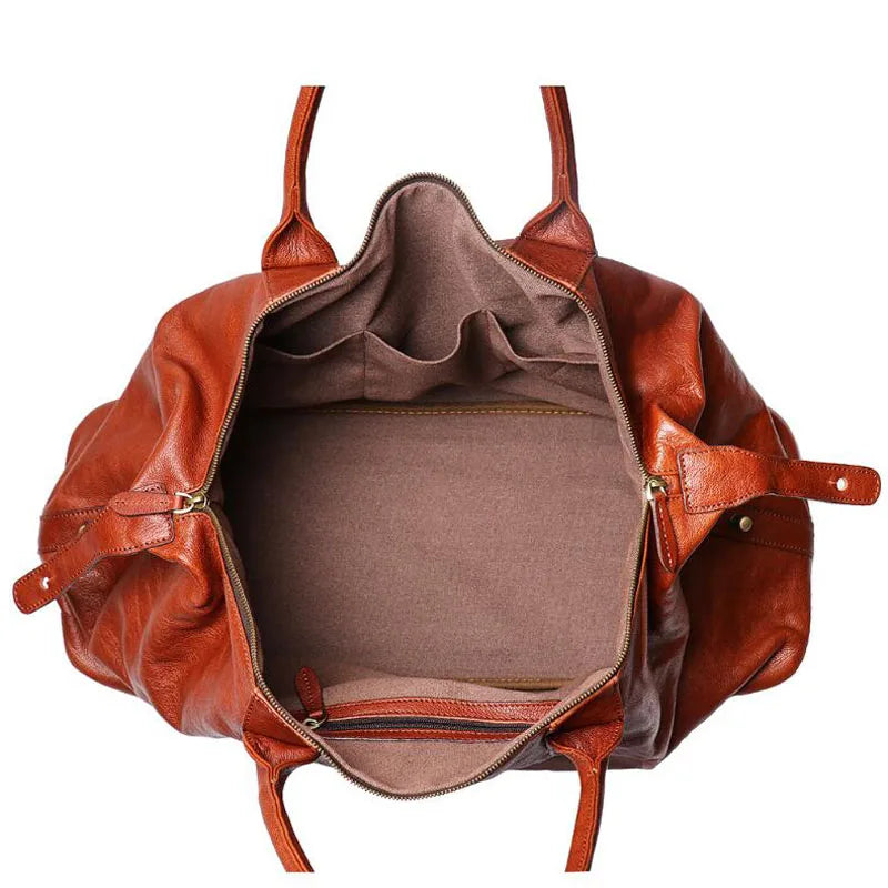 An open brown leather tote bag with dual top handles, showing a spacious interior lined with brown fabric, set against a plain white background.