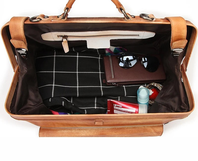 Open brown leather bag with various items on a white background