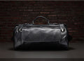 Black leather duffel bag against a dark brick wall