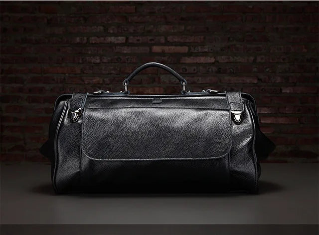 Black leather duffel bag against a dark brick wall