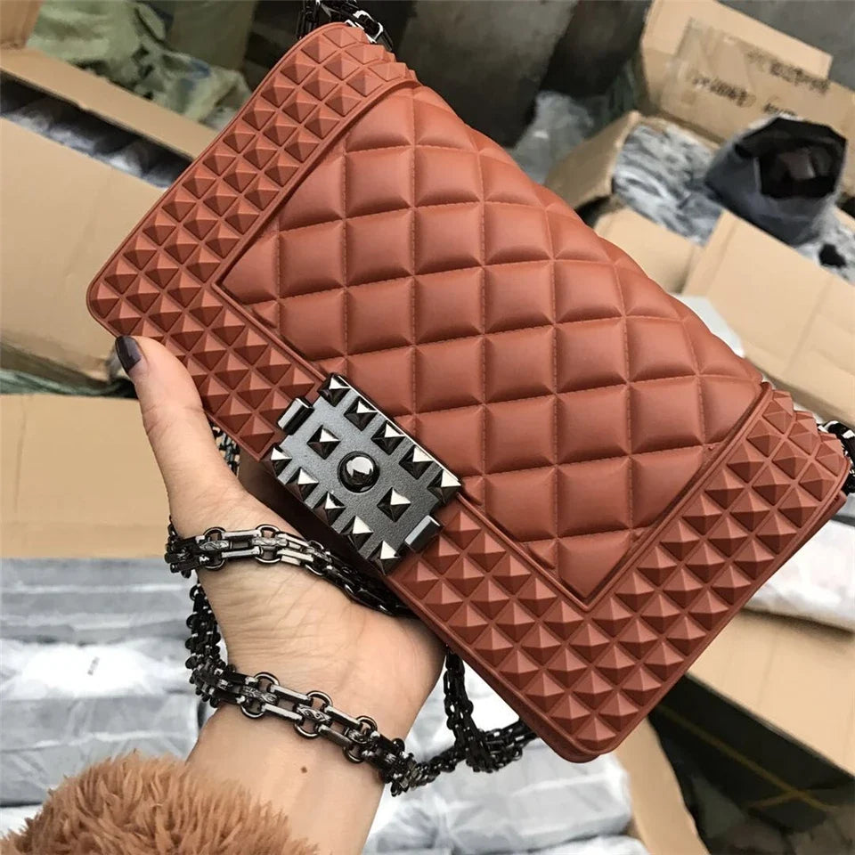 Brown quilted handbag with studded detail held by a person in a warehouse setting.