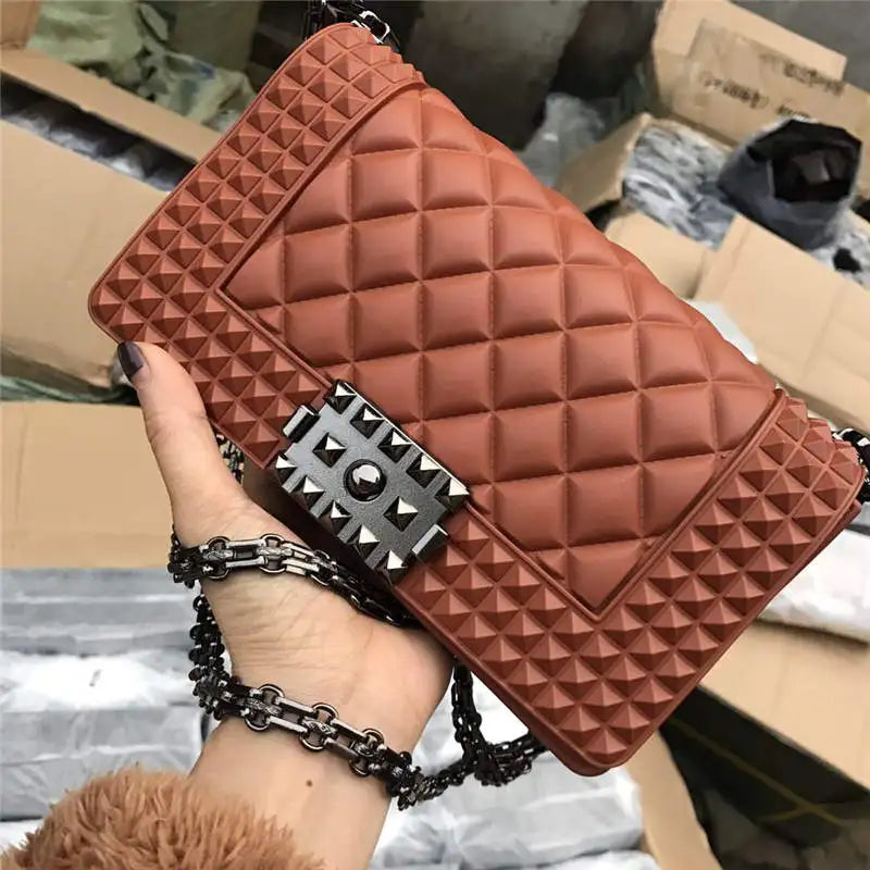 Brown quilted handbag with studded detail held by a person in a warehouse setting.