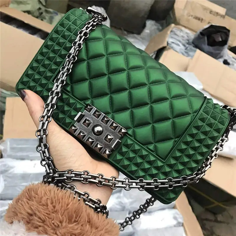 Green quilted handbag with chain strap held by a hand against a cluttered background