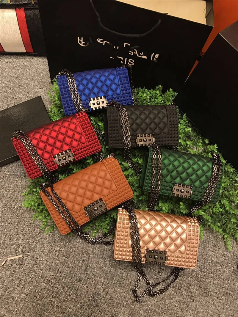 Collection of colorful quilted handbags on a textured surface with a black box in the background.