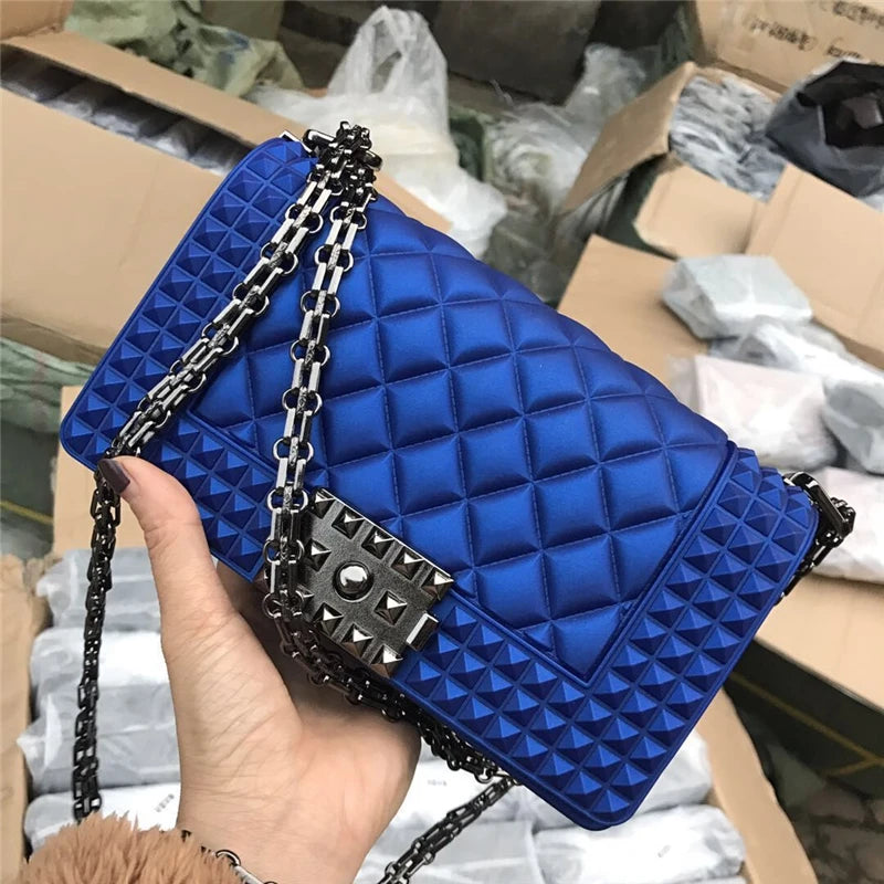 Blue quilted handbag with a chain strap held by a hand against a warehouse background.