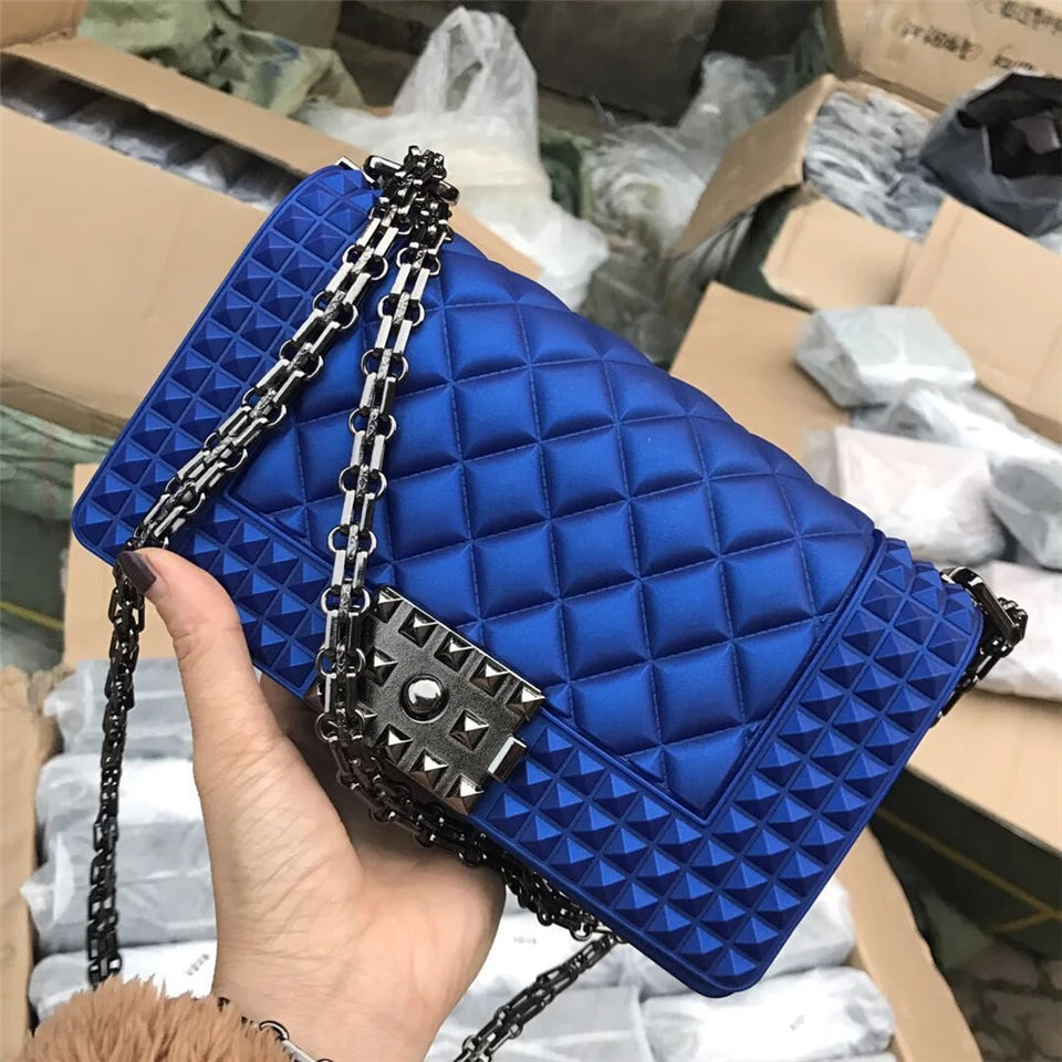 Blue quilted handbag with a chain strap held by a hand against a warehouse background.