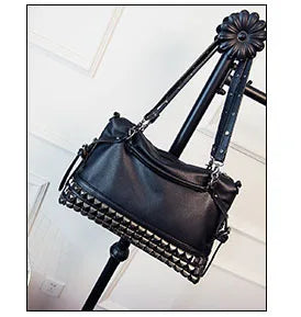 Black studded handbag on a stand against a white background