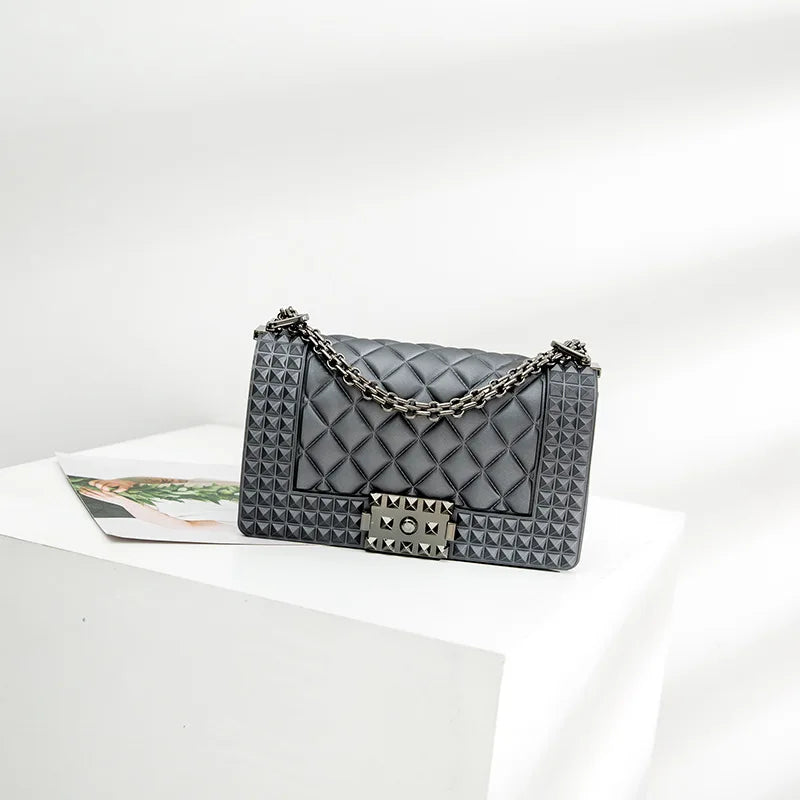 Gray quilted handbag with studded details on a white surface