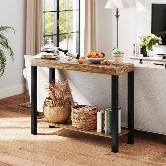 A rustic console table with a weathered wood top and black metal legs, styled in a bright living room with books, baskets, and home decor.