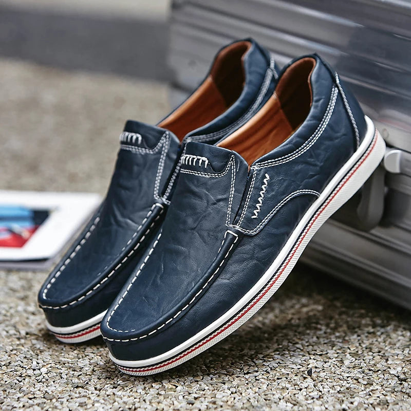 Pair of navy blue loafers with white stitching on a textured surface.
