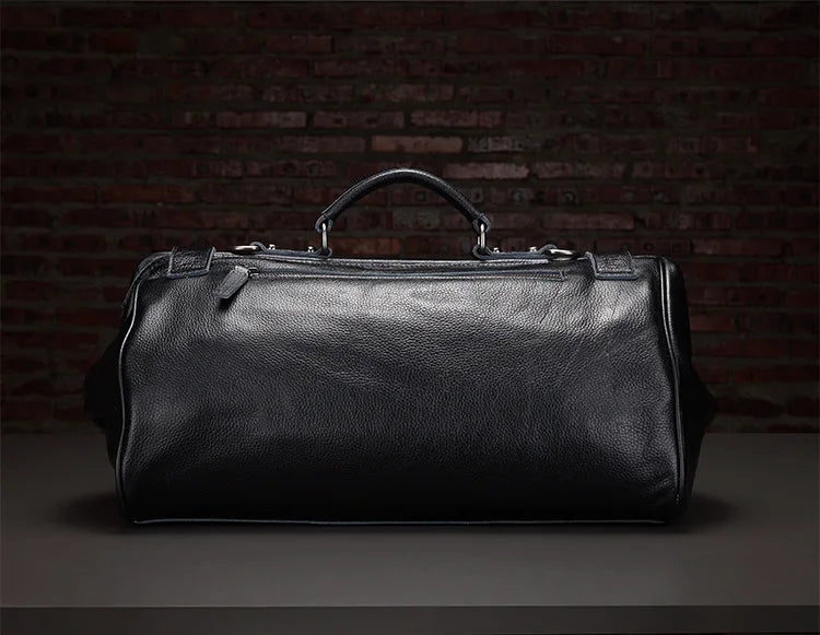 Black leather duffel bag against a dark brick wall