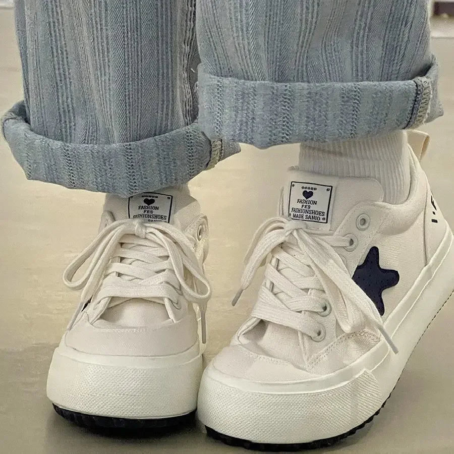 White sneakers with a star detail worn with light blue pants and white socks.