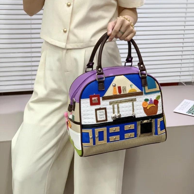 Person holding a colorful handbag with a house design in an indoor setting