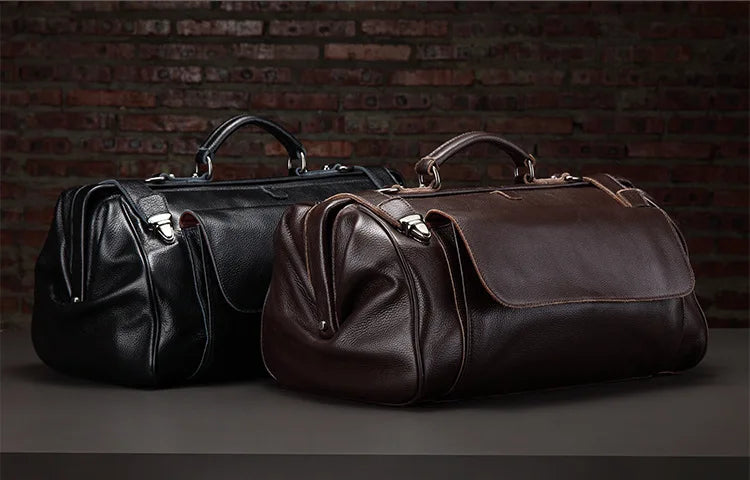 Two leather bags, one black and one brown, against a brick wall.