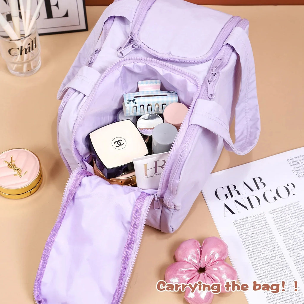 Purple bag with cosmetic items on a beige surface with a magazine.