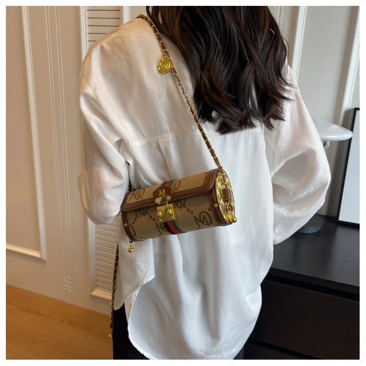 A person wearing a white blouse carries a Gucci GG Supreme canvas shoulder bag with a gold chain strap in an indoor setting.