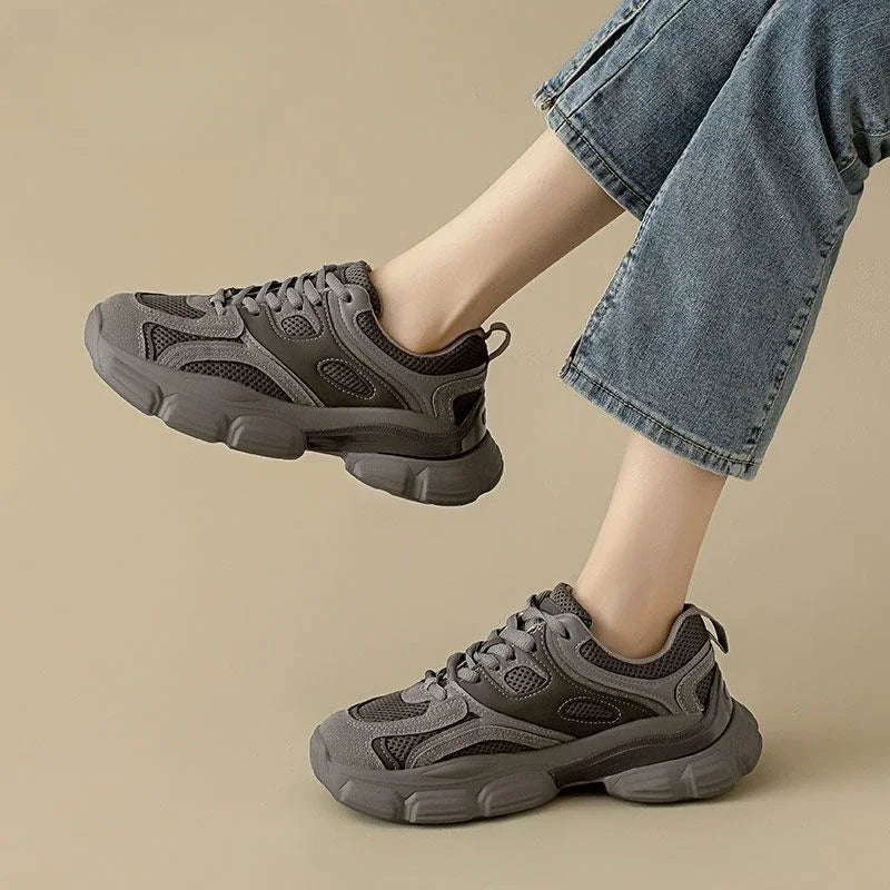 Gray sneakers worn with blue jeans on a beige background