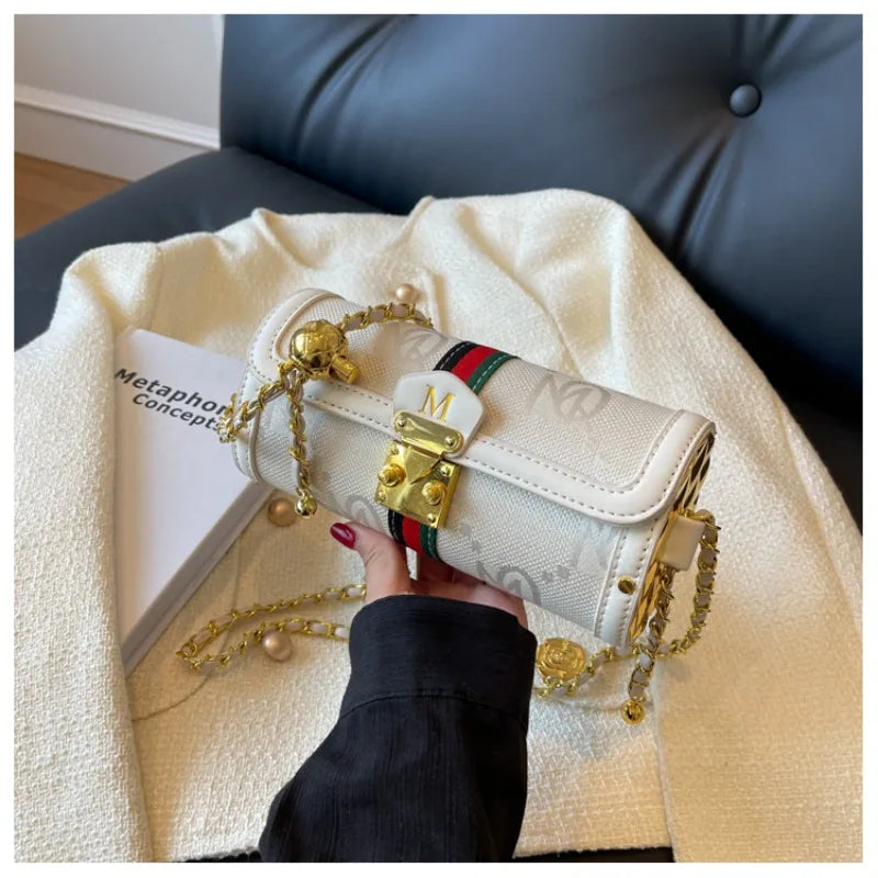 White handbag with gold chain and red, green, and blue stripe held by a person on a textured surface.