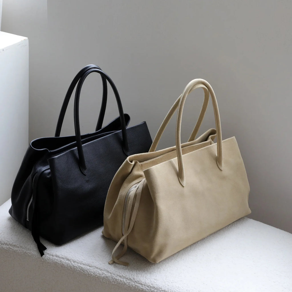 Black and beige handbags on a white surface with a neutral background